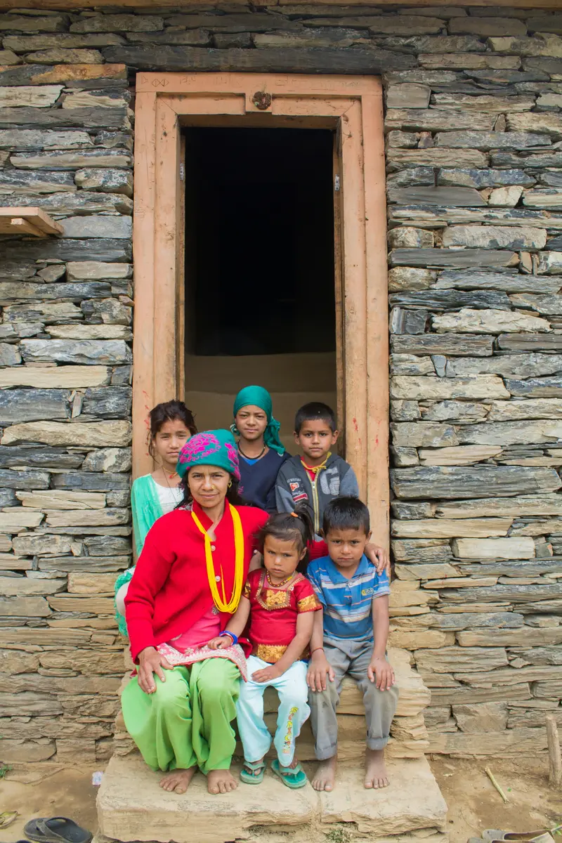 A family sitting in the doorway of their stone house in Nepal