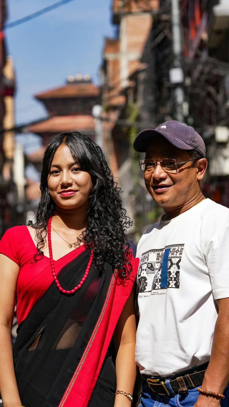 A young woman and an older man in glasses on a street in Nepal
