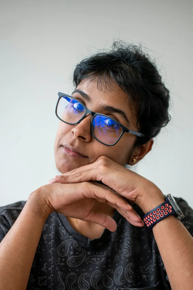 Woman in blue-light glasses, chin resting on her hands