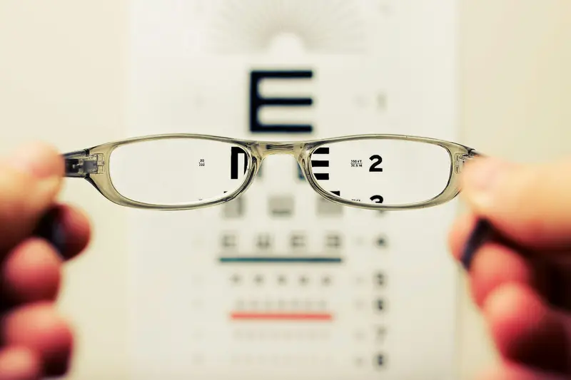 Glasses held up in front of an eye chart